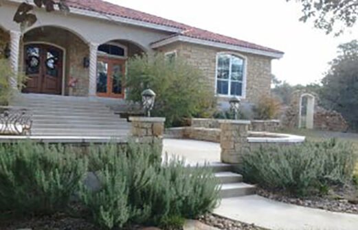 The rosemary and anacacho orchic trees work with the rock retaining walls, columns and arches to create an old world feel to this entry--River Chase